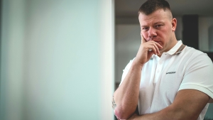 man in white shirt with hand to his mouth; thinking 