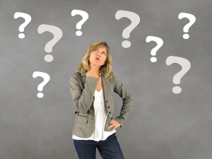 woman looking thoughtful against gray background with question marks above her