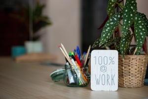 desktop with plant, container with pens and sign that says 