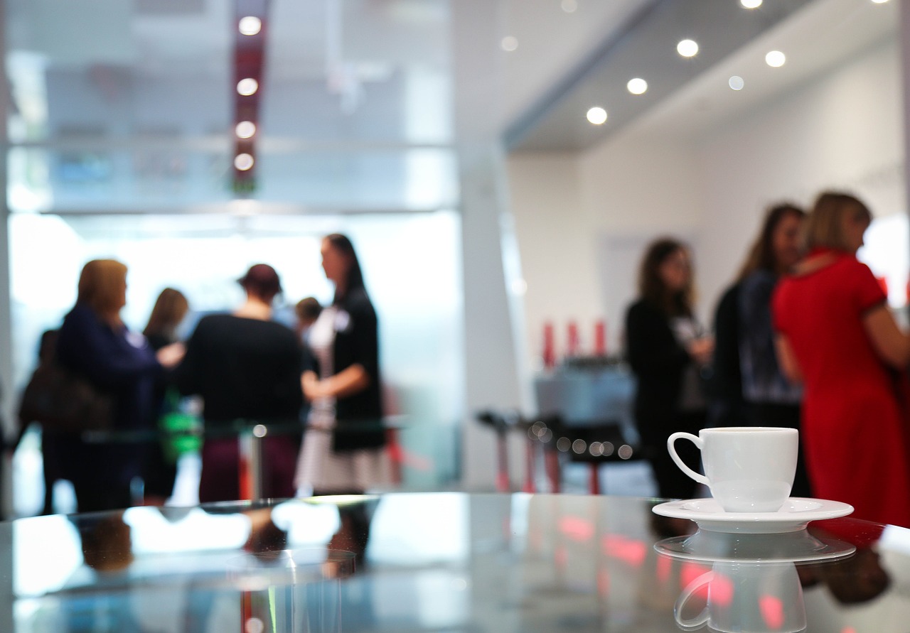 image of coffee cup on table with lots of people in background,; conference, event